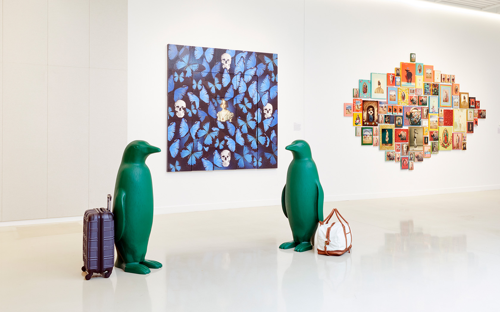 two sculptures of green penguins with luggages next to them 
