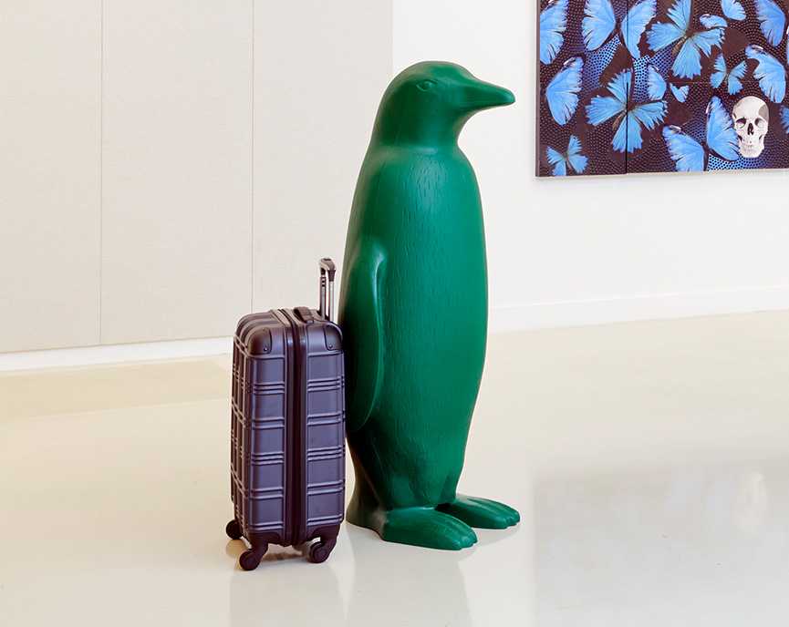 green penguin with suitcase next to it
