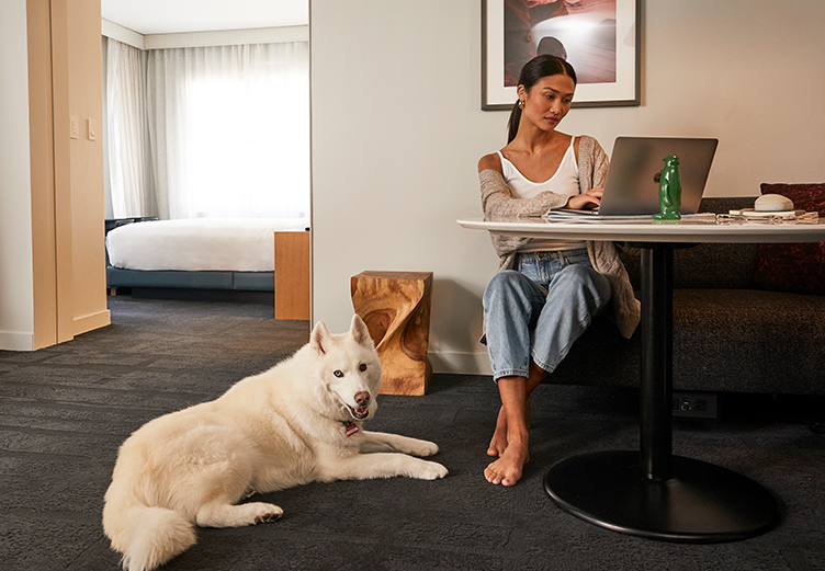 woman on computer with white dog next to her