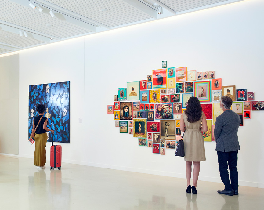 people looking at 2 large art installations on the wall