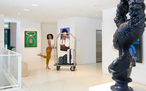 woman posing with luggage cart in art exhibit