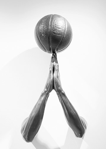black and white shot of hands praying and a basketball balancing on top