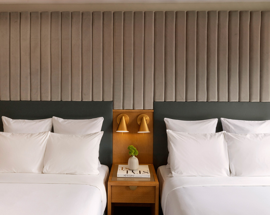 Two queen sized bed with a bed side table in the middle