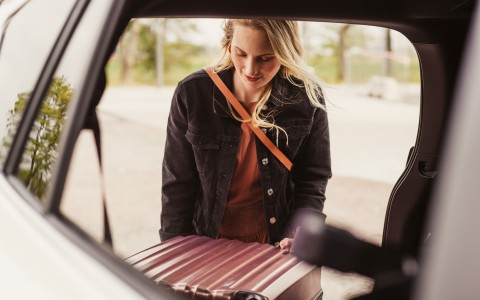 Girl packing a suitcase in a car