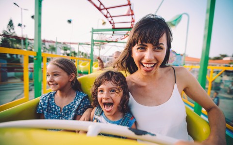 mom and 2 kids smiling on a rollercoaster