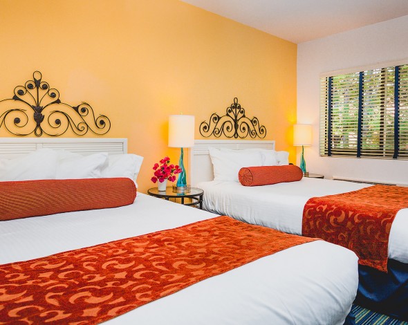 two hotel beds with yellow walls