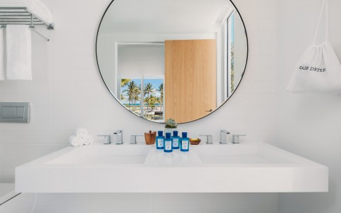 view of a stylish bathroom with features as a circle mirror and white accents 