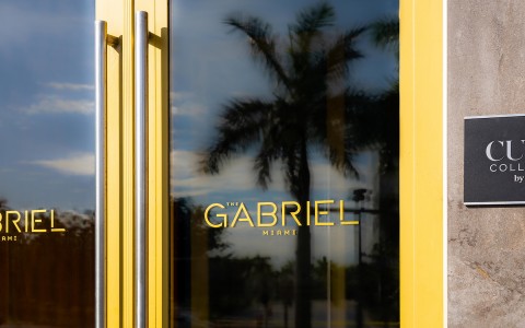 glass door with gabriel hotel logo reflecting a palm tree