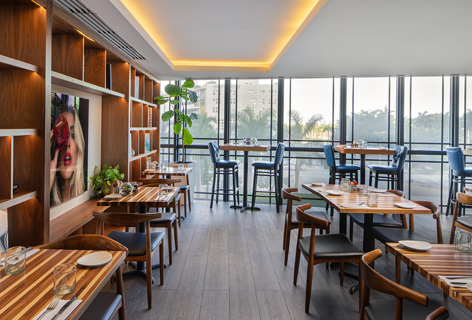 view of a restaurant space with multiple tables and tall tables and a blonde girl poster on the side of the wall
