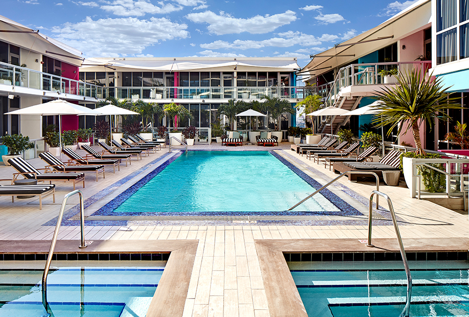 view of long rectangular pool lined with sun lounge chairs and umbrellas