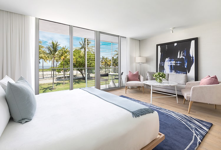 king sized bed with a view to the beach through the large windows and balcony