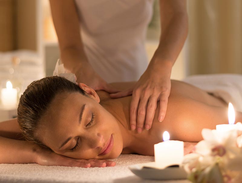 woman getting a back massage with a candle as decoration