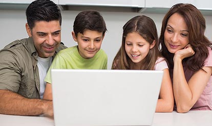 Family of two kinds and the parents looking at something on the laptop 