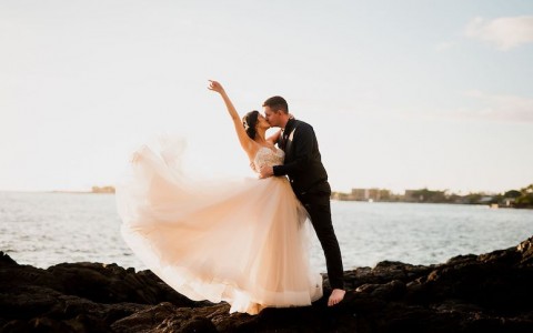 bride and groom kissing on rocks