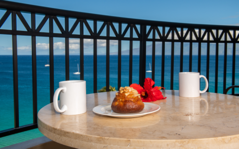 coffee mug and pastry atop lanai table with ocean in the background