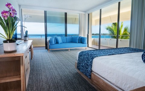 corner king room with blue couch overlooking the ocean