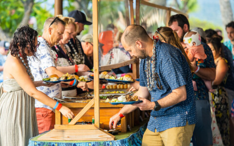 men and women enjoying buffet with Hawaiian and Asian cuisine 
