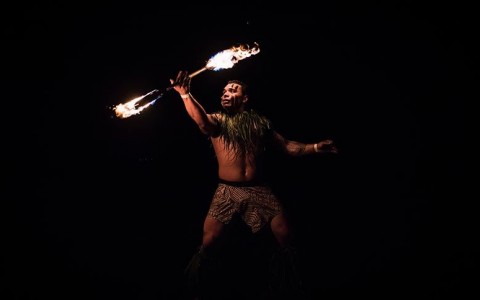 man holding a wooden stick with fire on both ends