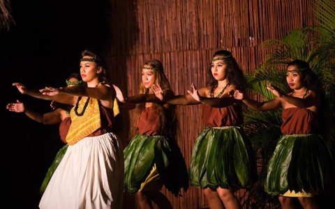 three people hula dancing with grass skirts