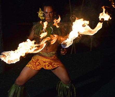 man in traditional hawaiian attire with fire 