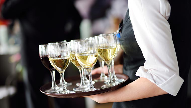 waitress holding a tray with white wine glasses 