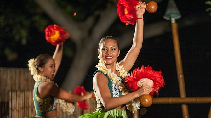 Woman dancing in a luau with red maracas on the hands 