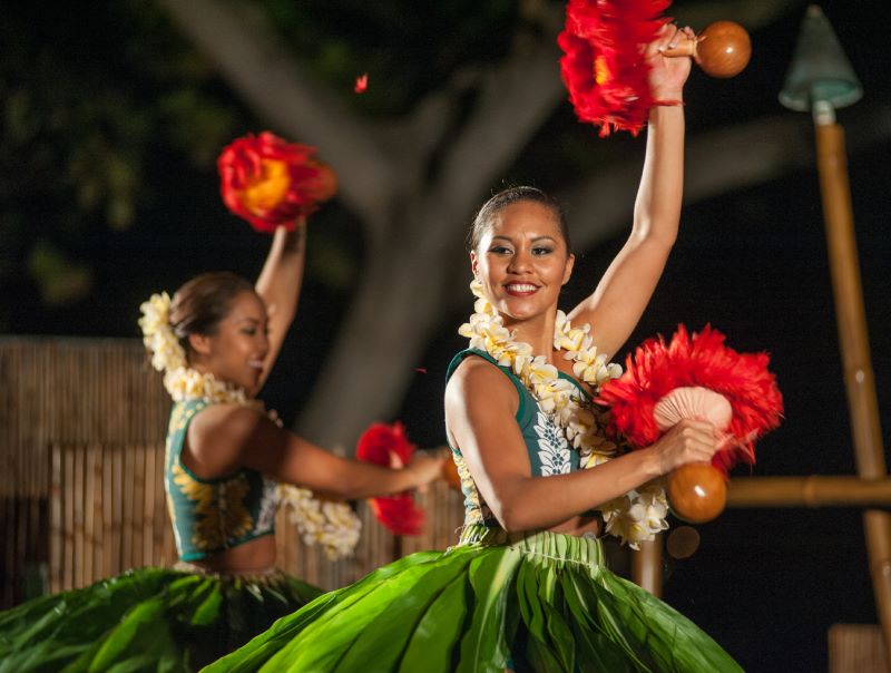 Woman dancing in a luau with red maracas on the hands 