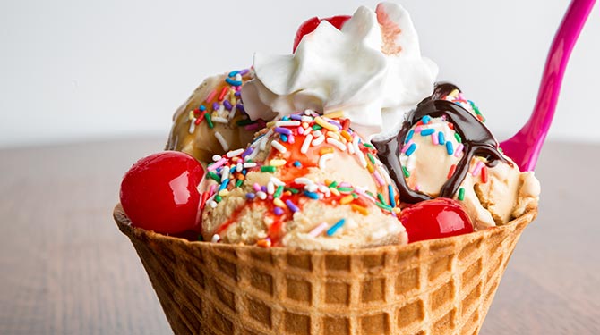 ice cream with sprinkles, cherries and whipped cream in a waffle cone