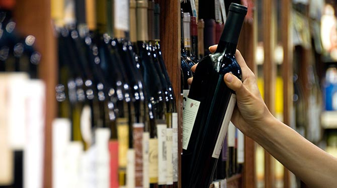 a person choosing from a variety of wine bottles on a shelf