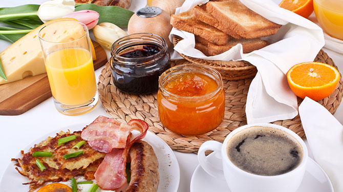close up of breakfast served table with jams, ham, hash brown, and orange juice 