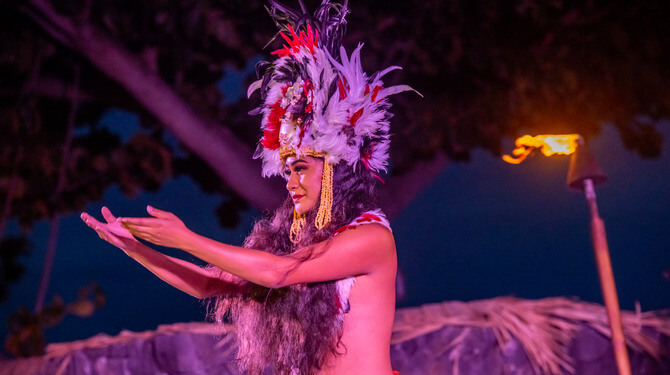 women dancing in luau with burning tiki torch in background 