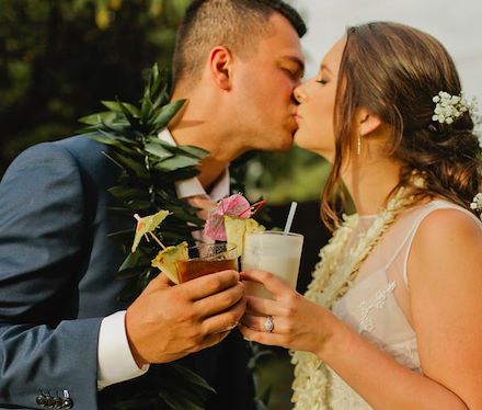 couple just married kissing and holding cocktails