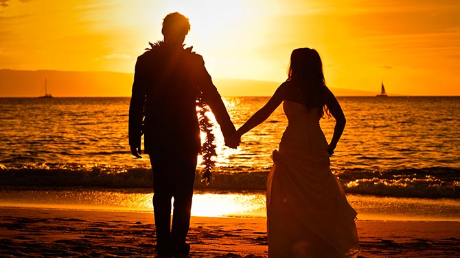 newlyweds walking off into the ocean at sunset