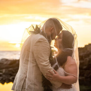 wedding couple together on sandy beach with oceanfront views during sunset 