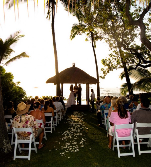 wedding couple holding hands in a gazebo while other people look on