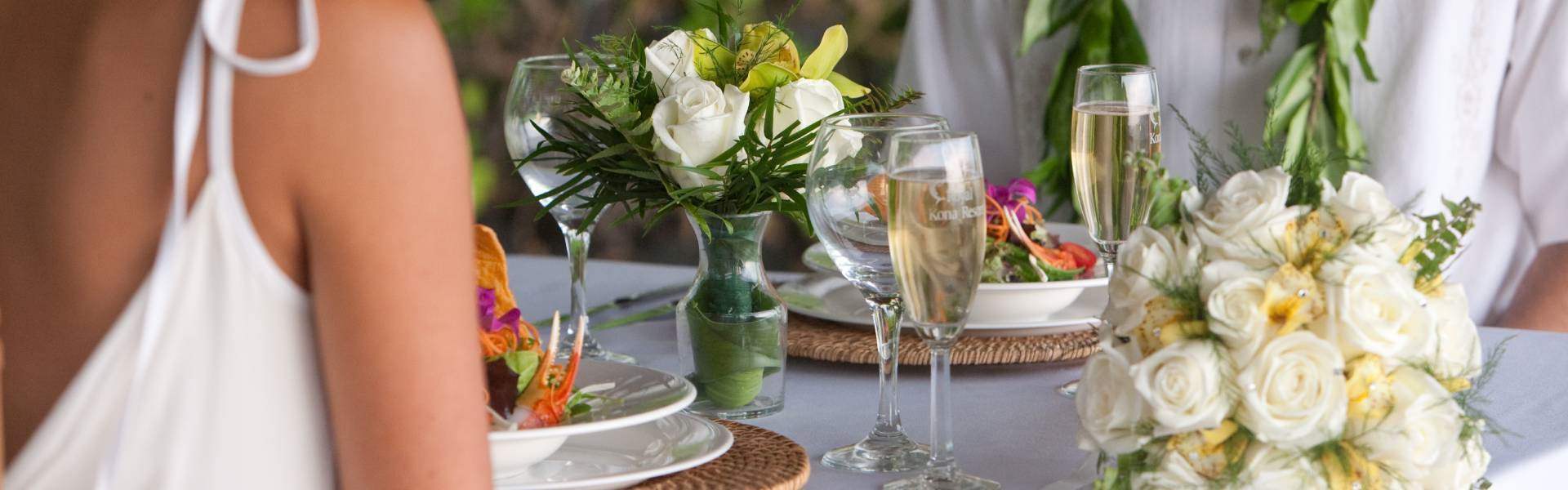 zoomed view of white flowers on a vase and champagne in flutes