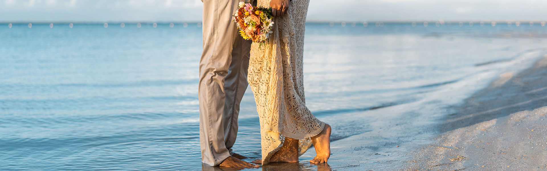 couple standing on the beach with feet in the water