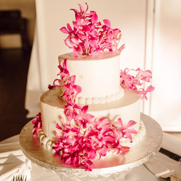 two-tiered wedding cake with pink tropical flowers