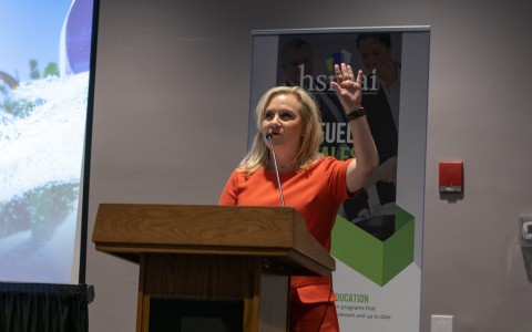 woman with hand up at podium