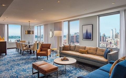 manhattan suite living room with blue and grey couches and 8 person dining room table 