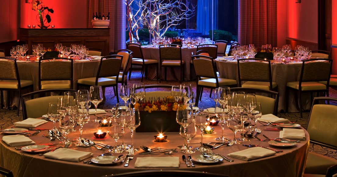 event room with dim red an blue lighting, 3 round tables fully set