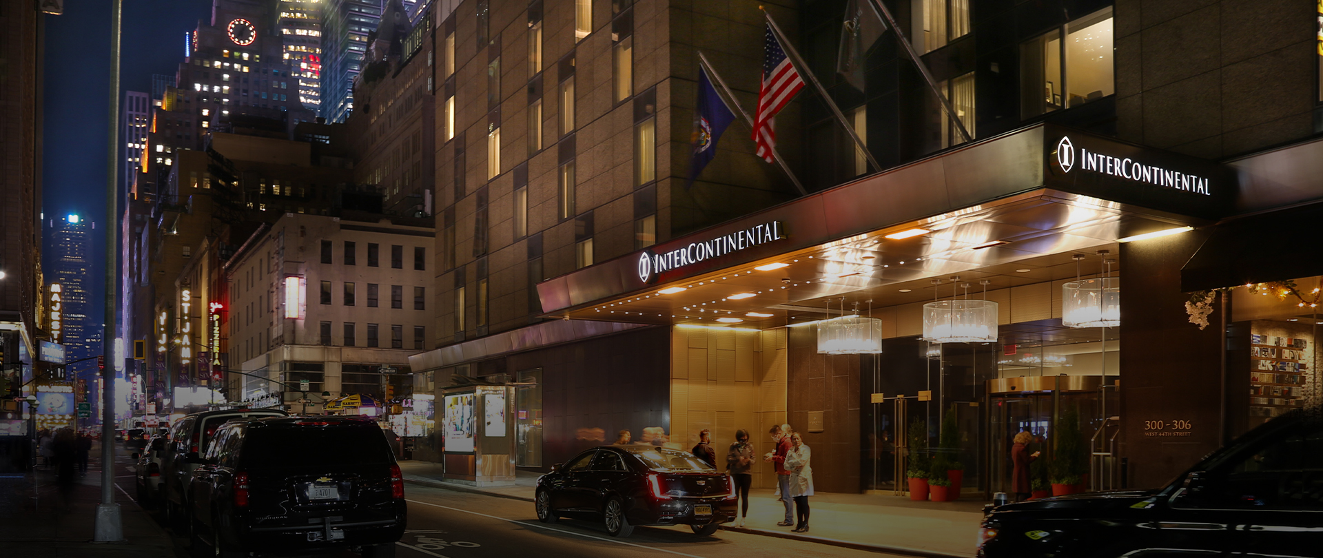 intercontinental hotel exterior view. cards driving by, people walking nearby, new york city in the night time