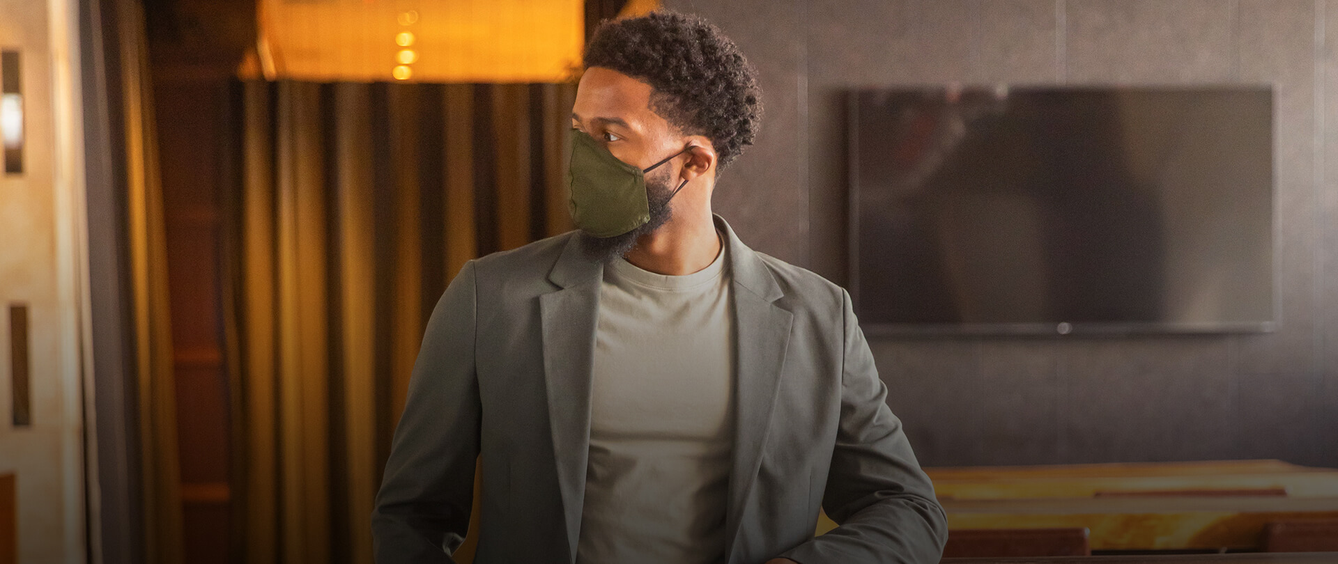 Man in business casual suit wearing a black face mask 