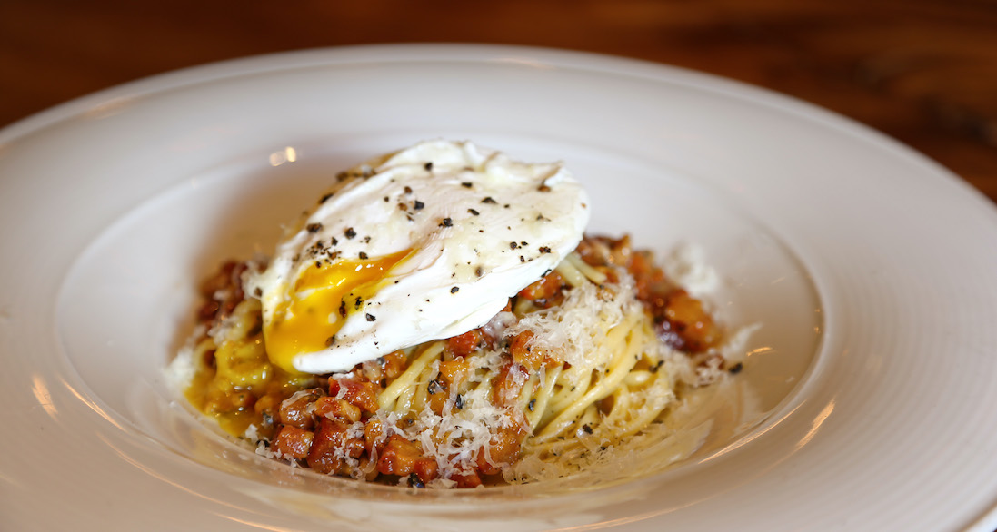 spaghetti on a plate with fresh tomato sauce and an over easy egg on top