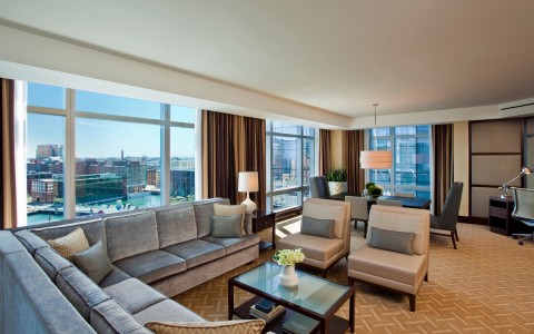 hotel room with a large couch, chairs, and a view of the city
