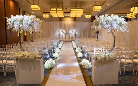 intercontinental boston venue with white chairs and white flowers and a walkway leading up to where the couple will marry