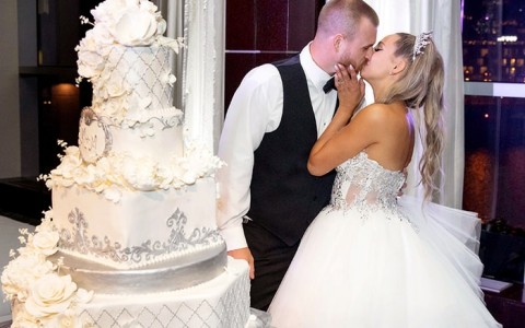 a bride and groom standing their next to their wedding cake, kissing