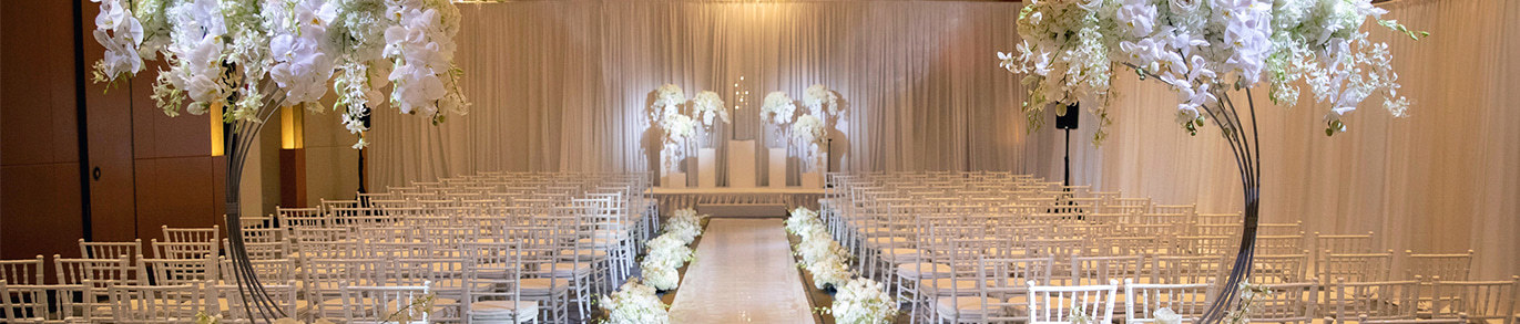 intercontinental boston venue with white chairs facing the altar that is covered with white roses 