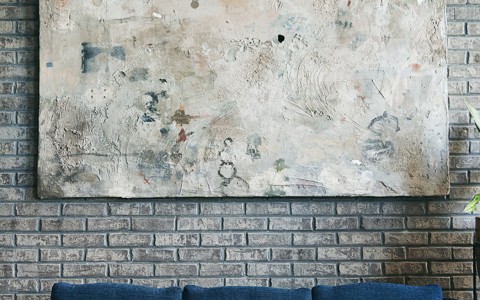blue couch with painting in background and brick walls