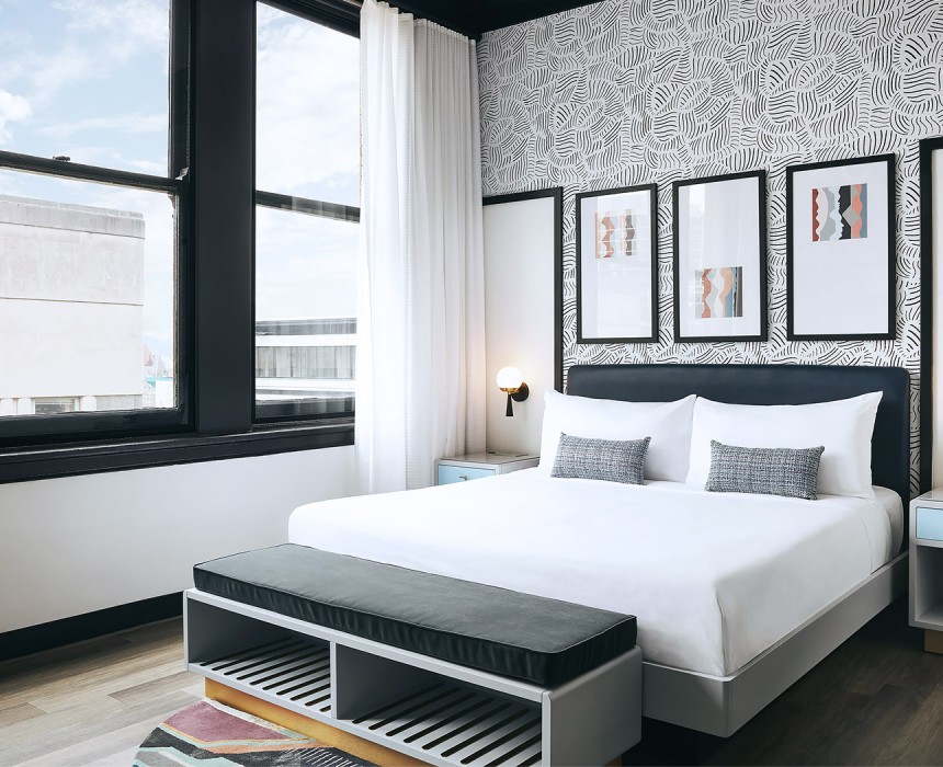 airy hotel room with bright windows and black and white wallpaper headboard